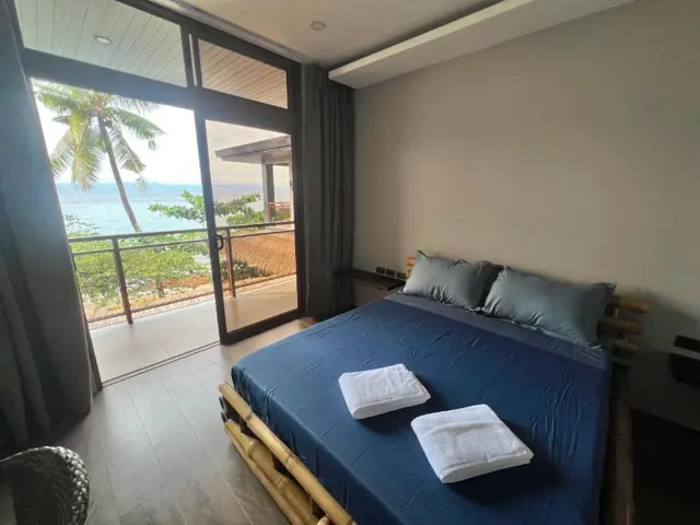 Bedroom with navy bedding and a sea-facing balcony